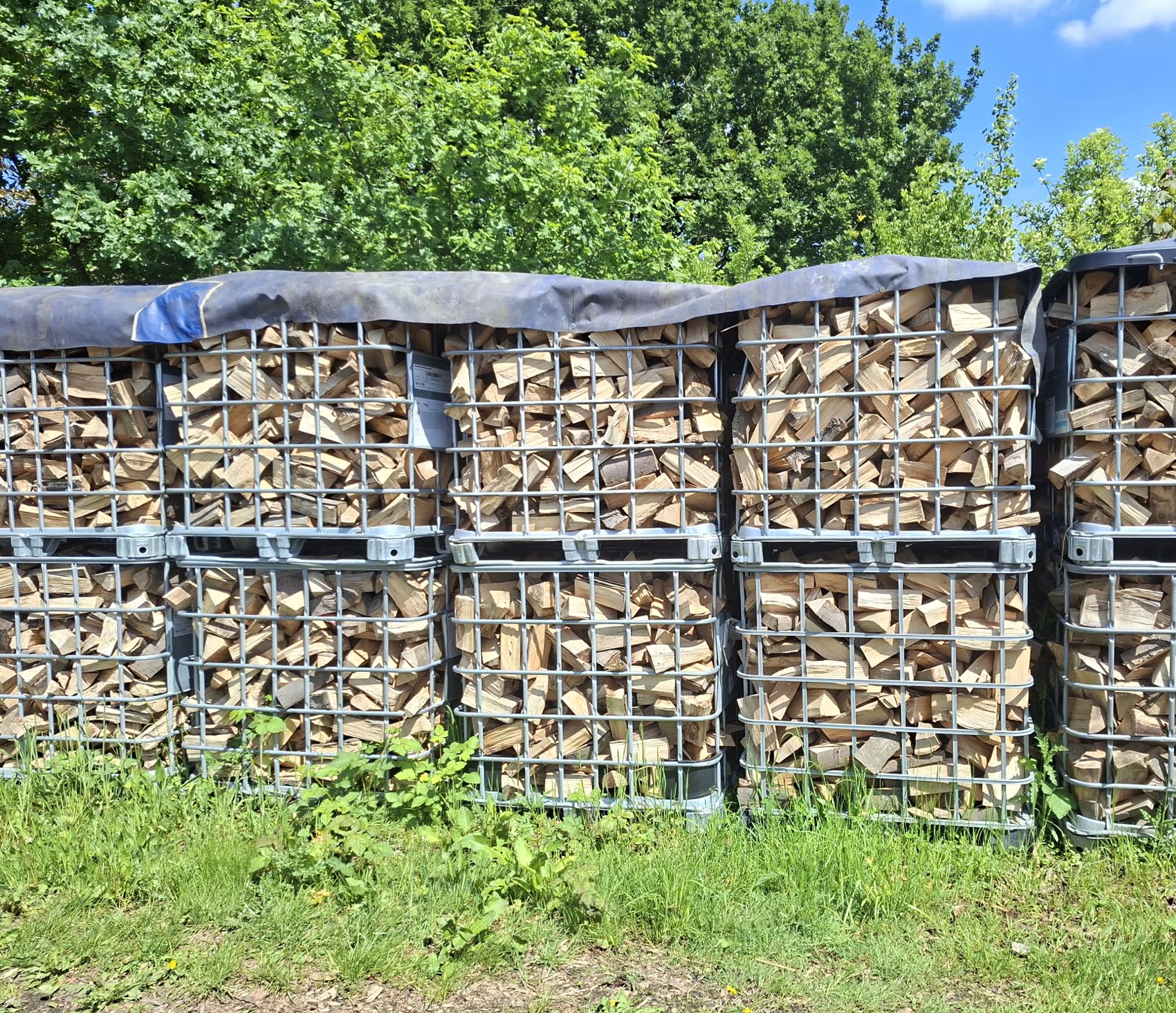 Gitterboxen mit gespaltenem Buchenholz, abgedeckt zum Trocknen