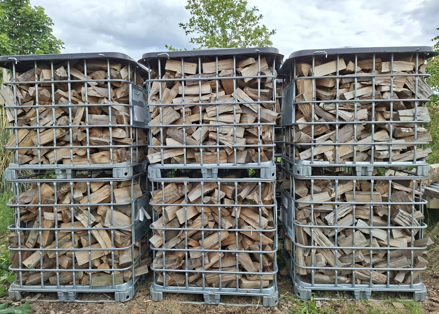 Holzlagerplatz in Krefeld-Fischeln: sechs Gitterboxen voll Brennholz, paarweise gestapelt