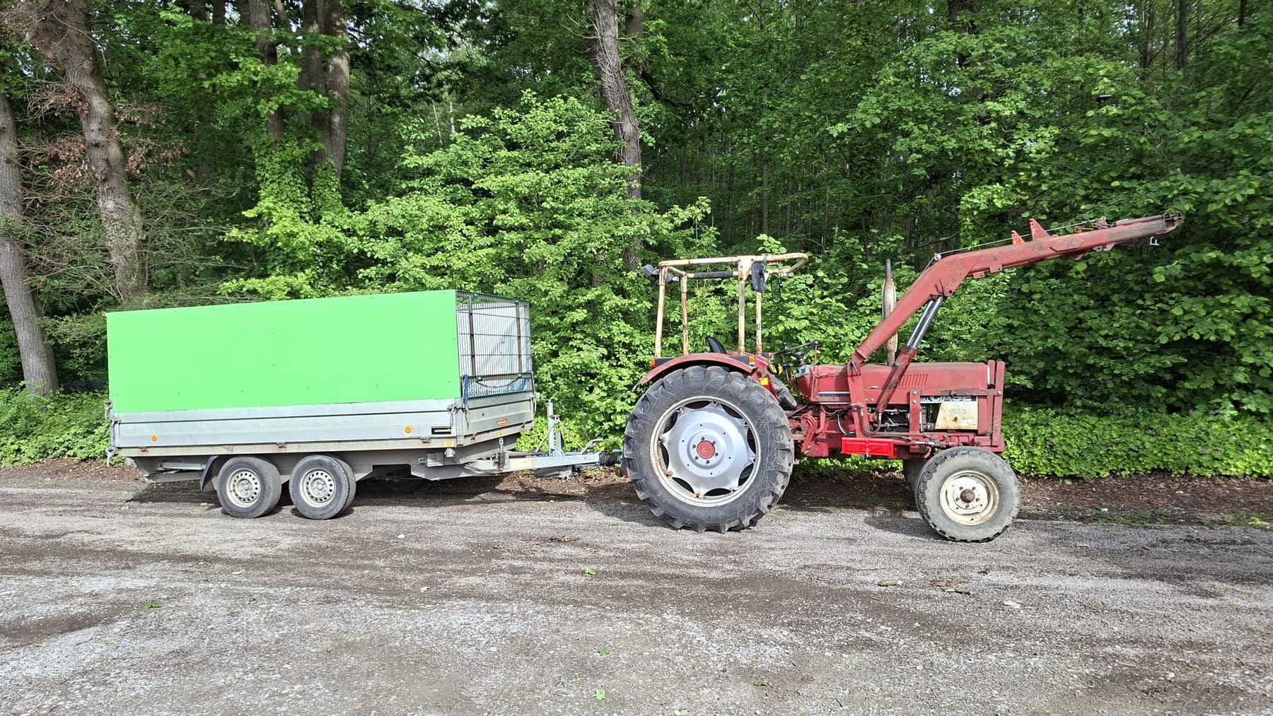 Traktor mit Anhänger am Waldrand beim Holzholen